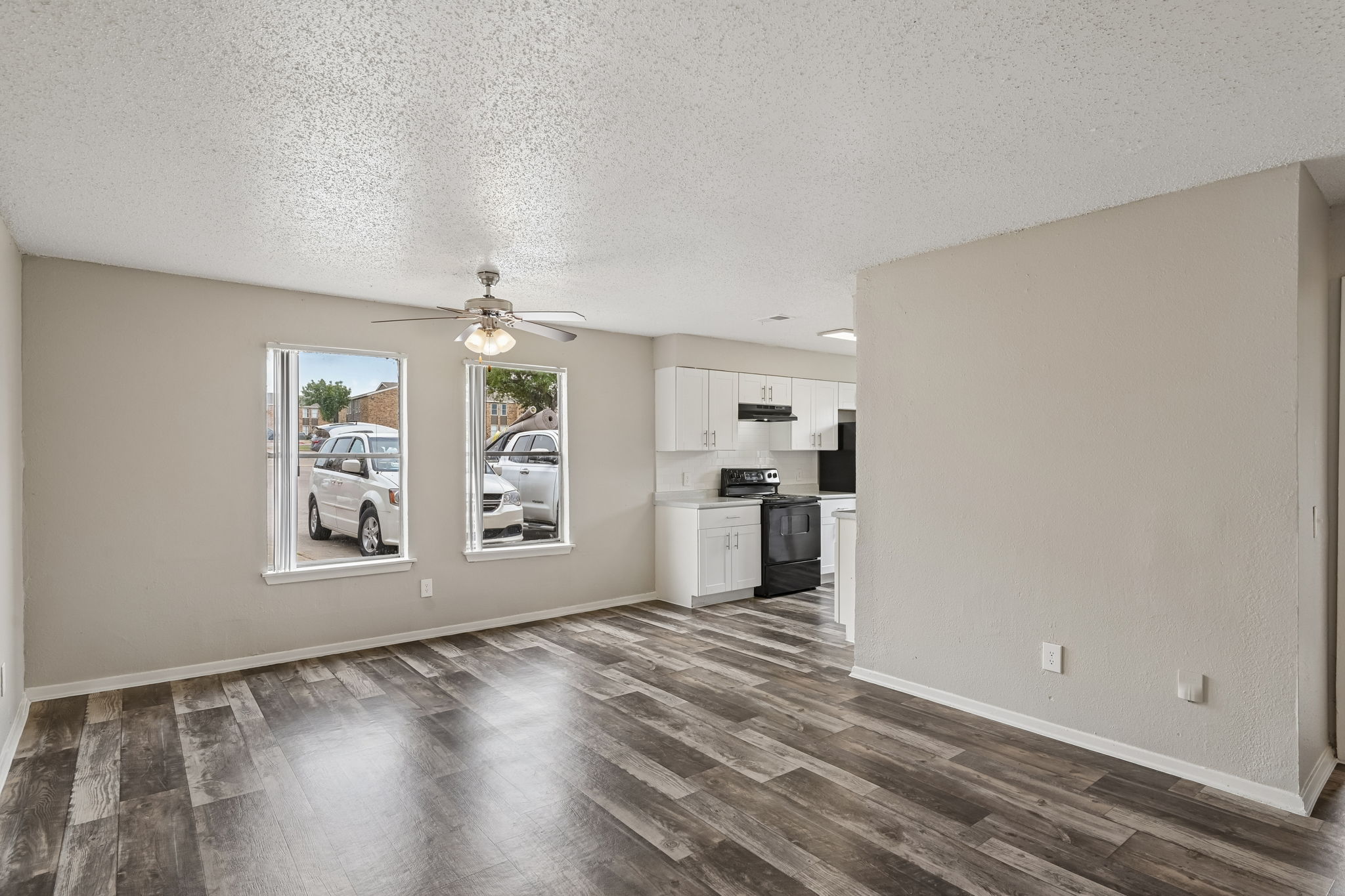A spacious room with a wooden floor and a ceiling fan.